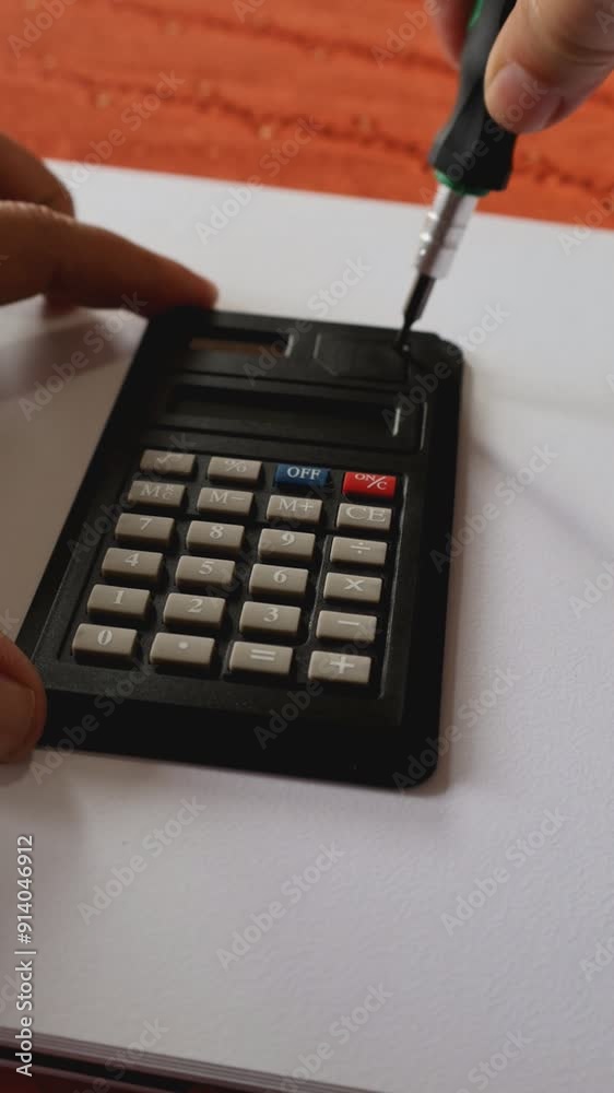 Caracas, Venezuela-07 de julio 2024: Primer plano de unas manos de mujer cambiando la batería o pila a una calculadora que dejo de funcionar. Video vertical.