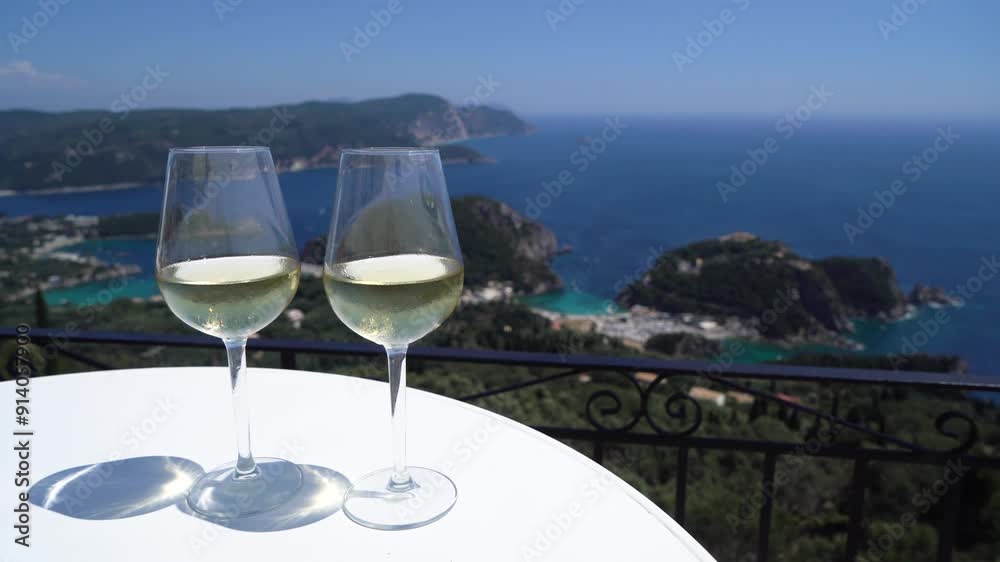 Pouing white wine intoglasses with Corfu seascape in background