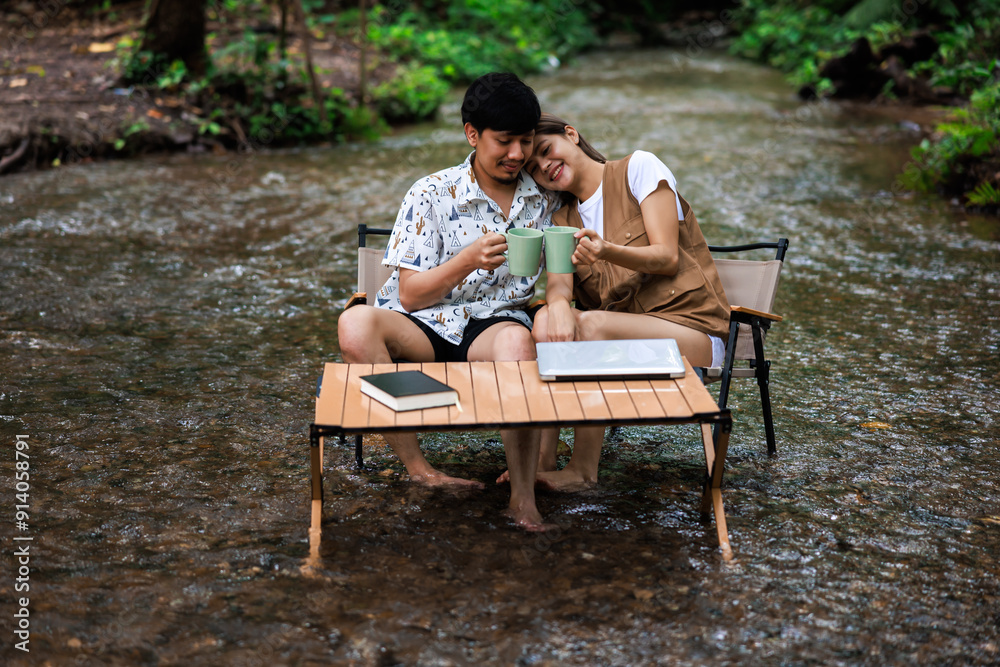 relax and romantic time concept, young asian couple enjoying sitting on wooden chairs drinking coffee together in middle of a stream relax and romantic time concept, young asian couple enjoying sitting on wooden chairs drinking coffee together in middle of a stream