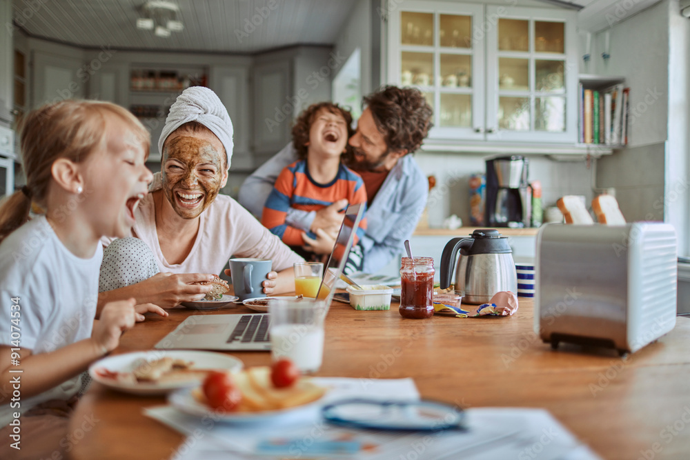 Happy family enjoying breakfast together in modern kitchen with laptop Happy family enjoying breakfast together in modern kitchen with laptop