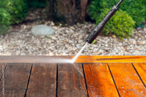 cleaning terrace with a power washer - high water pressure cleaner on wooden terrace surface