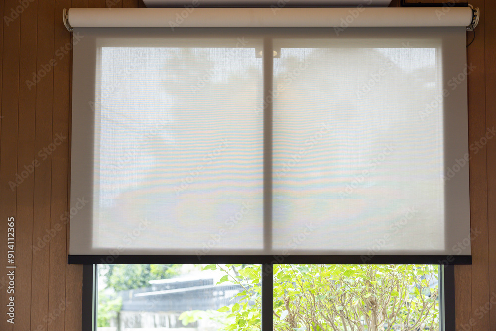 A white blind is drawn over a window, with a view of a tree outside A white blind is drawn over a window, with a view of a tree outside