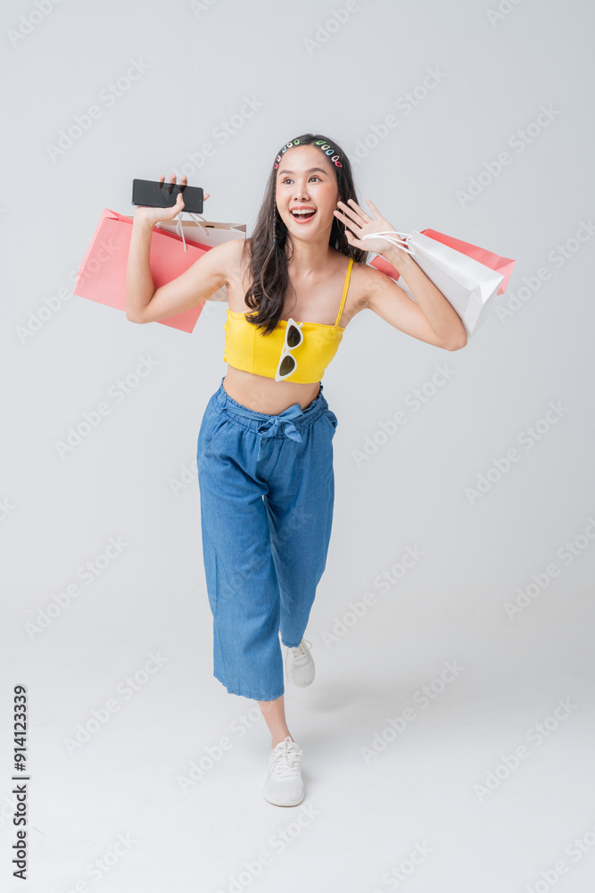 Asian happy female woman girl holds colourful shopping packages standing on plain background studio shot, Close up Portrait young beautiful attractive girl smiling hand hold colorful shopping bag Asian happy female woman girl holds colourful shopping packages standing on plain background studio shot, Close up Portrait young beautiful attractive girl smiling hand hold colorful shopping bag