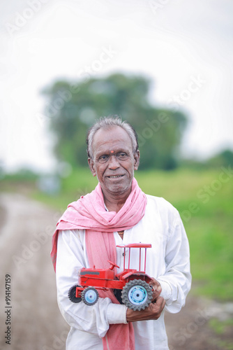 Indian farmer, equipped with a miniature tractor toy photo