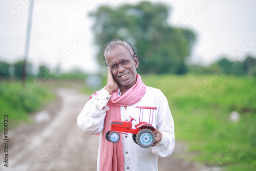 Indian farmer, equipped with a miniature tractor toy photo