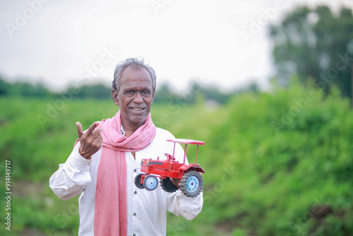 Indian farmer, equipped with a miniature tractor toy photo