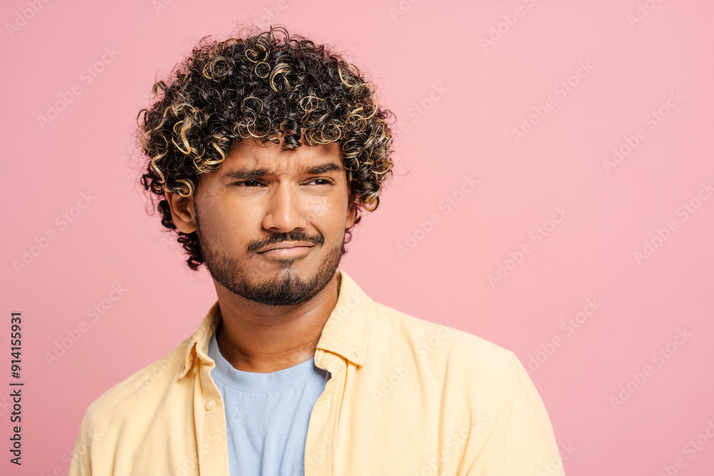 Young man with curly hair showing disapproval on pink background Young man with curly hair showing disapproval on pink background