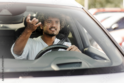 Young man getting angry while driving and gesturing through windshield