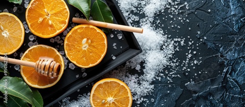 Winter themed flat lay featuring dry oranges honey a wooden spoon a toy sled and Rhododendron adamsii on a black tray against a snowy background with copy space image photo