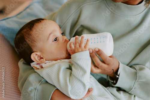 Foto Medium close up of caring female hands holding her son and bottle with formula t