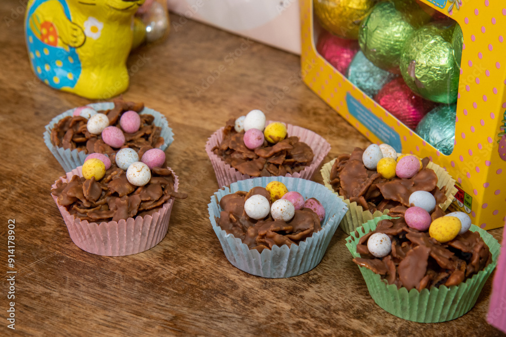 A selection of Easter Chocolate nest Cakes topped with little chocolate mini eggs on a wooden table