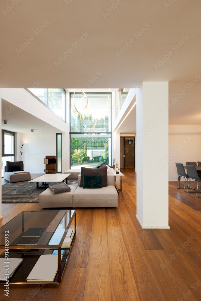 Fototapeta premium Modern living room with large sofa, with chaise longue, central coffee table, above a large carpet. Interior of a modern house on two levels