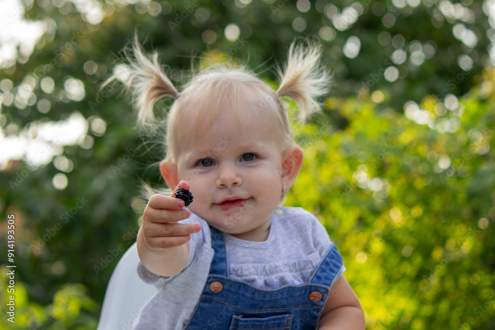little happy girl eating blackberry. Selective focus