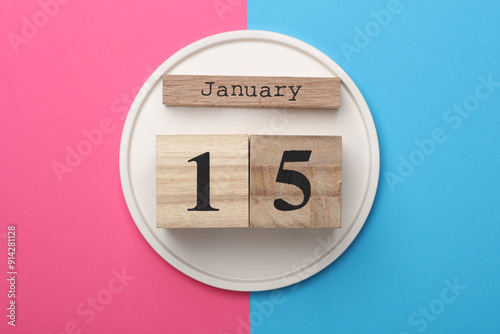 Wooden block calendar with the date january 15 on pink blue background. Top view