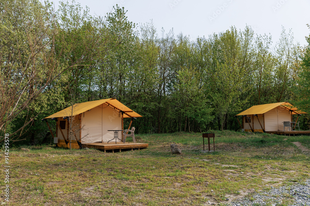 Cozy open glamping tents with light inside in summer camp. Camping tent for holiday and vacation Cozy open glamping tents with light inside in summer camp. Camping tent for holiday and vacation