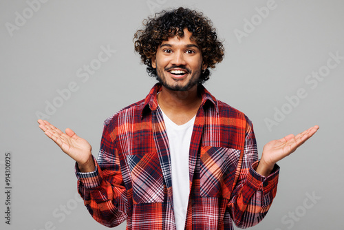 Young happy shocked surprised excited overjoyed cool Indian man he wears red shirt casual clothes look camera spread hands isolated on plain grey color background studio portrait. Lifestyle concept. photo