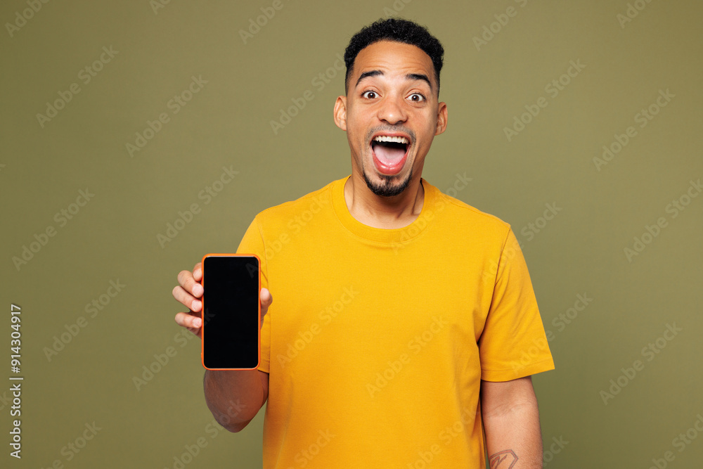 Young man of African American ethnicity he wears yellow t-shirt casual clothes hold in hand use mobile cell phone with blank screen area isolated on plain pastel green background. Lifestyle concept. Young man of African American ethnicity he wears yellow t-shirt casual clothes hold in hand use mobile cell phone with blank screen area isolated on plain pastel green background. Lifestyle concept.