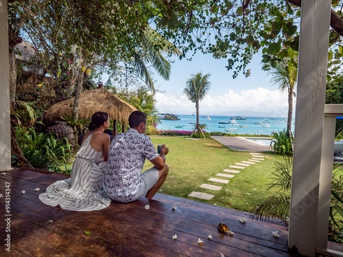 Photography Couple enjoying a tropical beach view from a wooden deck.