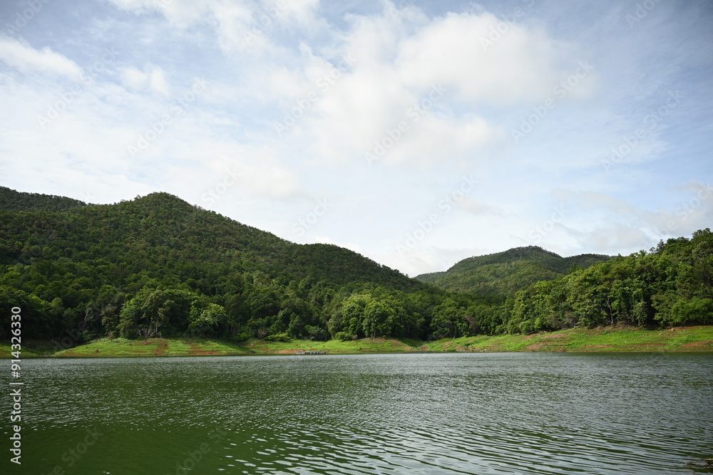 Scenic Lake and Mountain View, A serene lake bordered by lush green hills under a bright, partly cloudy sky, offering a peaceful and picturesque natural landscape Scenic Lake and Mountain View, A serene lake bordered by lush green hills under a bright, partly cloudy sky, offering a peaceful and picturesque natural landscape