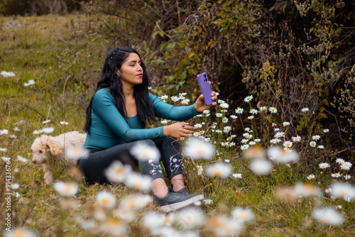 Mujer joven con teléfono móvil aislado sobre fondo naturaleza flores durante la publicidad y expresión facial .comunicación charla con celular. photo