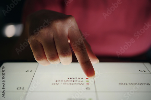 Close-up shot of hand interacting with touchscreen device during business presentation in dark setting, showing detailed information on screen