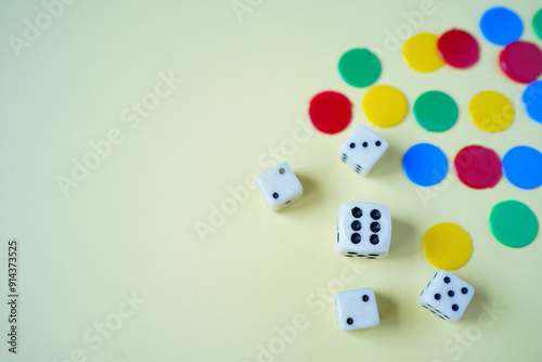 White dices and colorful tokens on yellow background.