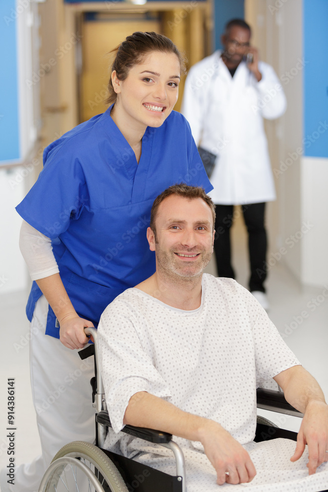 Fototapeta premium happy female doctor carrying male patient on wheelchair