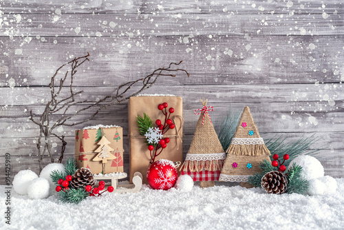 Christmas gift boxes, handmade decorative Christmas trees, tinsel and a Christmas ball in the snow.  Christmas and New Year decorations. photo