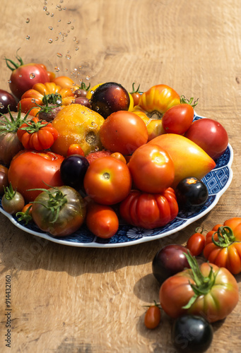 Obraz na płótnie Fresh colorful heirloom tomatoes on a plate washed with cold water outside on wooden rustic table. w salonie