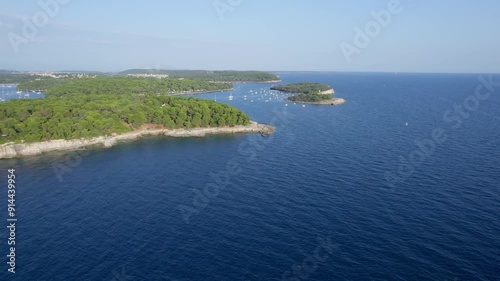 A stunning view captured by drone along the shores of the Mediterranean Sea. The beautiful Croatian coast during a summer vacation, with boats and yachts slicing through the sea waters.
