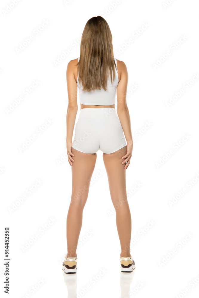 Sporty fit woman in white shorts and shirt isolated on white background. Full body of slim attractive female with flat belly. Back, rear view. Sporty fit woman in white shorts and shirt isolated on white background. Full body of slim attractive female with flat belly. Back, rear view.