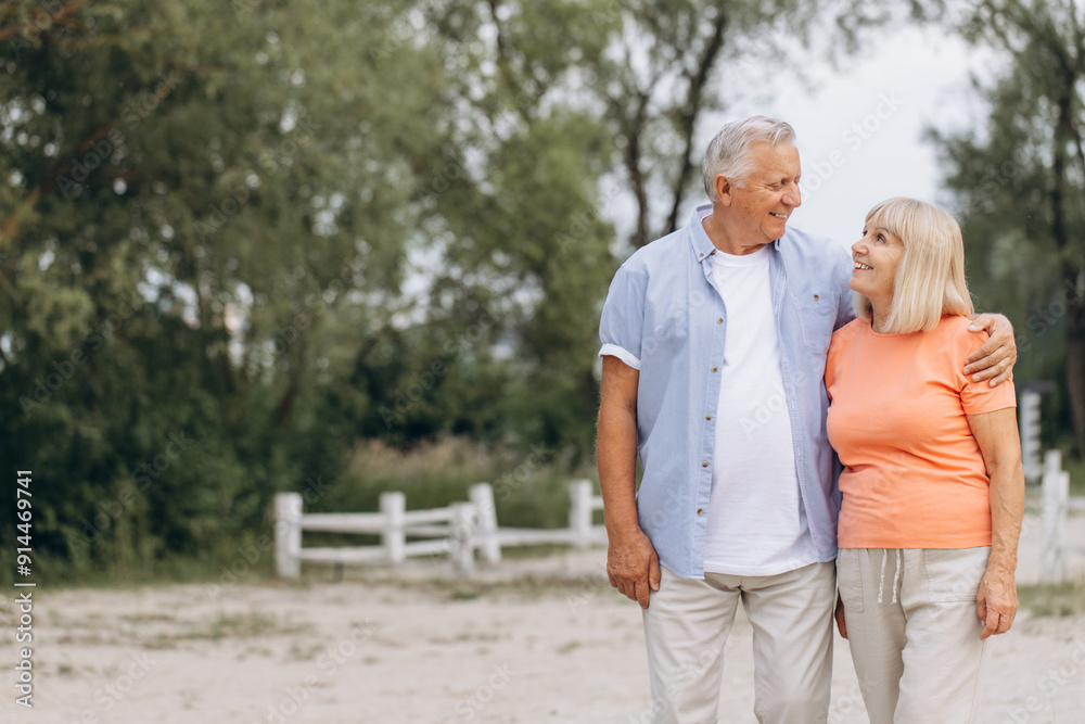 Obraz premium Happy Elderly Couple Enjoying a Walk in Nature on a Sunny Day