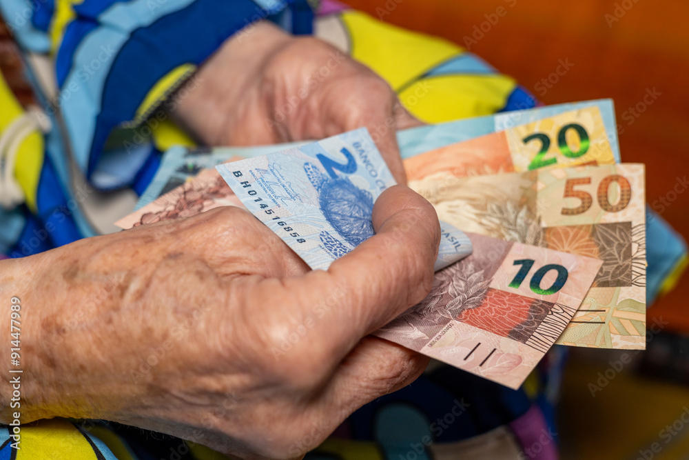 Pensioner's finances. An old lady counts Brazilian money, Pension in Brazil.