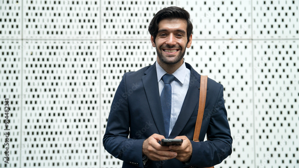 Portrait image of successful young business man looking at camera while hold phone with white background. Attractive caucasian investor or project manager standing at building. Close up. Exultant. Portrait image of successful young business man looking at camera while hold phone with white background. Attractive caucasian investor or project manager standing at building. Close up. Exultant.