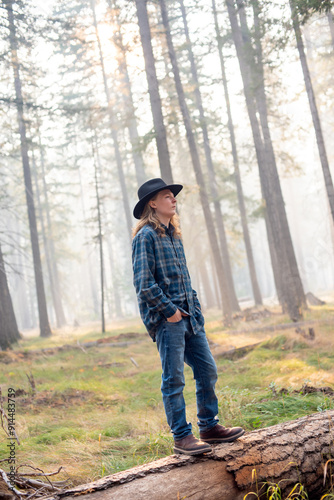 young man, wearing flannel shirt and jeans, walking though autumn forest