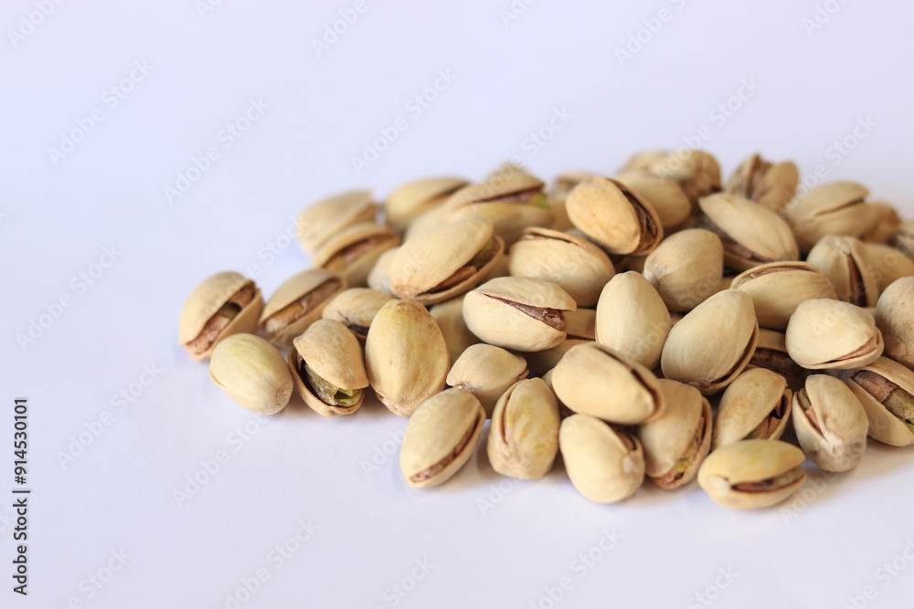 Pistachios on a white background. A handful of dry salted pistachios on a light background, selective focus. Pistachio with shell. Close-up Pistachios on a white background. A handful of dry salted pistachios on a light background, selective focus. Pistachio with shell. Close-up