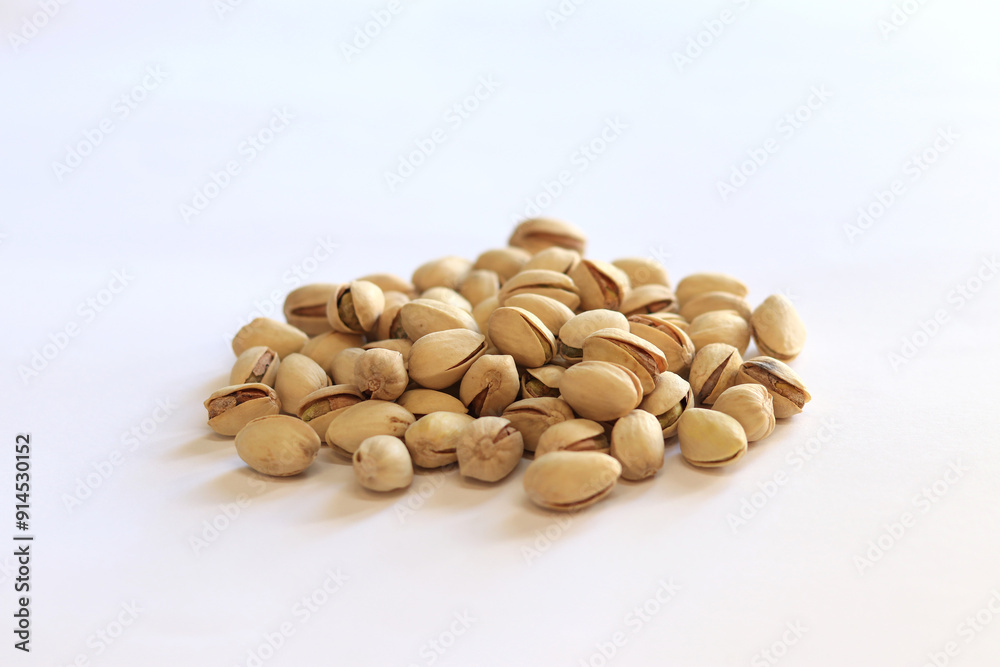 Pistachios on a white background. A handful of dry salted pistachios on a light background, selective focus. Pistachio with shell. Close-up Pistachios on a white background. A handful of dry salted pistachios on a light background, selective focus. Pistachio with shell. Close-up