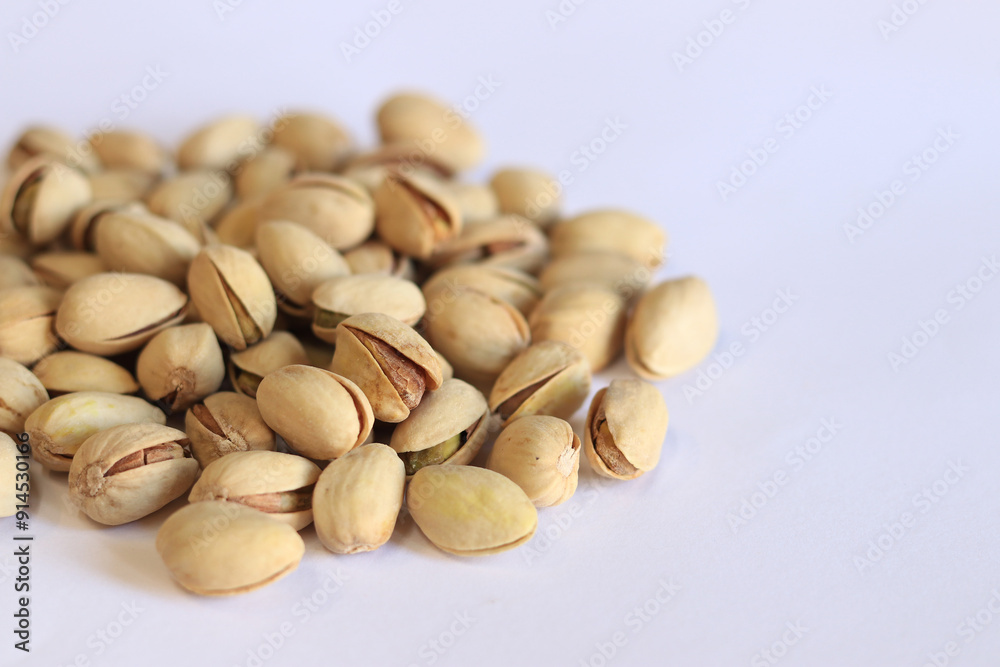 Pistachios on a white background. A handful of dry salted pistachios on a light background, selective focus. Pistachio with shell. Close-up Pistachios on a white background. A handful of dry salted pistachios on a light background, selective focus. Pistachio with shell. Close-up