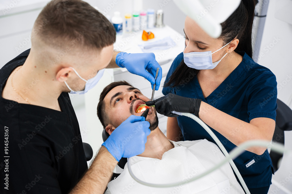 Initial examination of the patients oral cavity by dentist. Handsome man is having preventive dental checkup in clinic. Initial examination of the patients oral cavity by dentist. Handsome man is having preventive dental checkup in clinic.