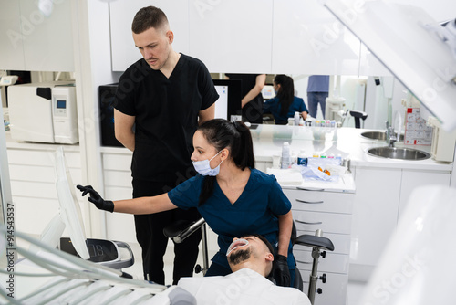 Digital teeth scanning preparation. Dentist and assistant preparing x-ray apparatus before digital teeth scanning in dental clinic.