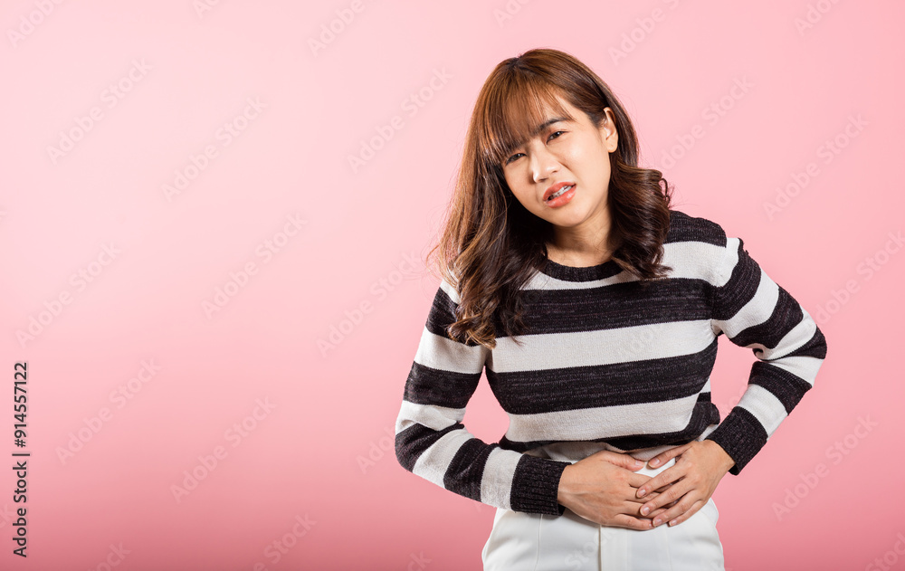 Portrait of Asian beautiful young woman has stomachache, female abdominal pain suffering from stomach ache, studio shot isolated on pink background, period pain, Health and medical gastritis concept Portrait of Asian beautiful young woman has stomachache, female abdominal pain suffering from stomach ache, studio shot isolated on pink background, period pain, Health and medical gastritis concept