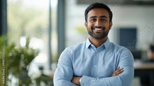 A person wearing a blue shirt stands with their arms crossed, looking confident