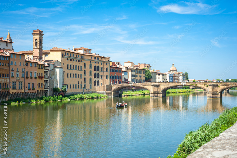 Fototapeta premium Rowing boat in the Arno River with historic buildings and the Santa Trinita Bridge in in Florence, Italy