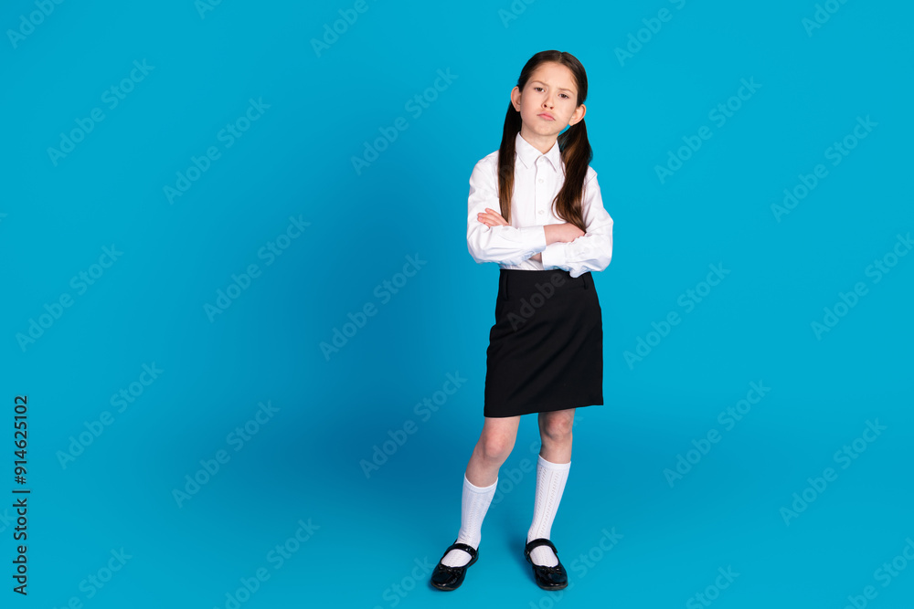 Full size photo of cute small schoolkid crossed arms empty space wear uniform isolated on blue color background Full size photo of cute small schoolkid crossed arms empty space wear uniform isolated on blue color background
