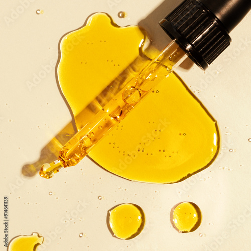 yellow oil pouring out of a pipette, drops of oil photo