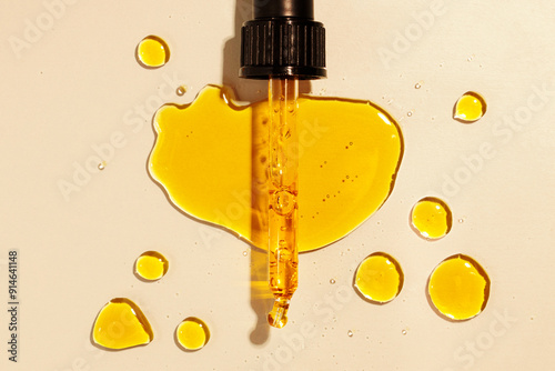 yellow oil pouring out of a pipette, drops of oil