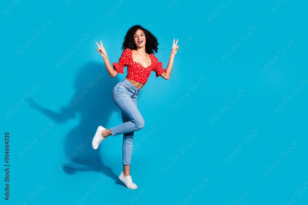 Full size photo of pretty young woman v-sign empty space wear top isolated on blue color background Full size photo of pretty young woman v-sign empty space wear top isolated on blue color background