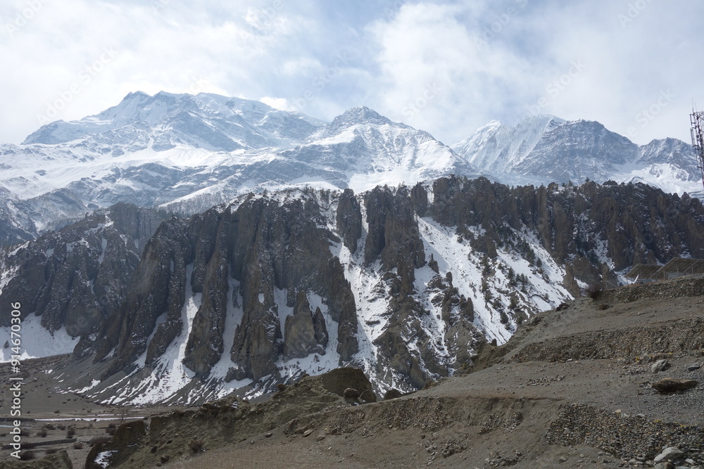 Serene rocky path winds through the majestic himalayas. With snow-capped mountains towering in the background under a partly cloudy sky Serene rocky path winds through the majestic himalayas. With snow-capped mountains towering in the background under a partly cloudy sky