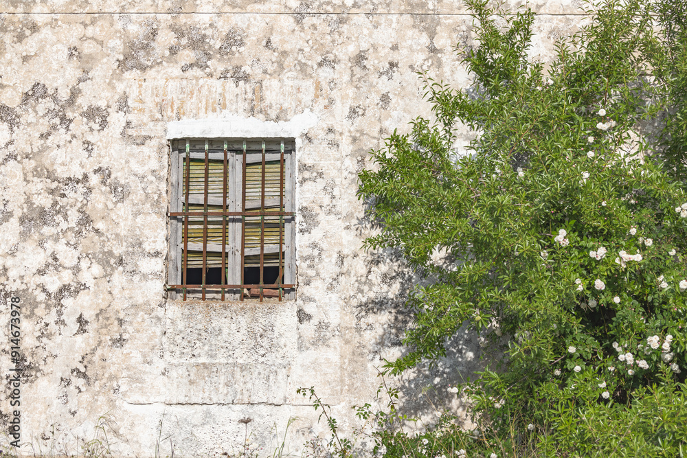 A barred window on an old stucco building.