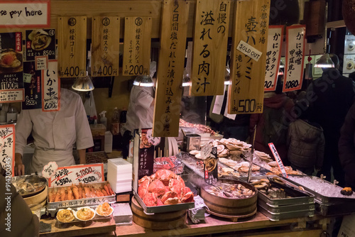 Kyoto, Japan - December 26, 2023: Grilled seafood for sale at the  Nishiki market. Japanese snacks - clams, shrimp, scallop, squid. photo